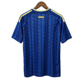 Blue sports jersey with yellow accents on a hanger against a light gray background