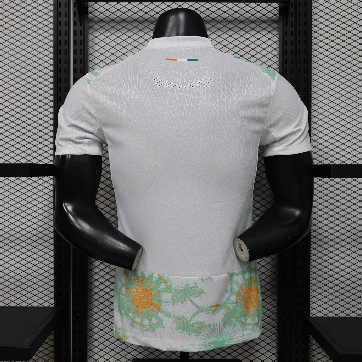 Mannequin wearing a white sports jersey with floral shorts against a black metal grid background