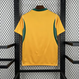 Yellow sports jersey with green accents on a hanger against a black metal fence background