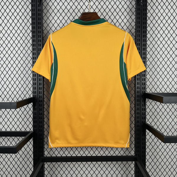 Yellow sports jersey with green accents on a hanger against a black metal fence background