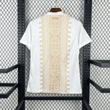 White t-shirt with gold geometric pattern on a hanger against a black metal grid background