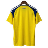 Yellow sports jersey with blue and white accents on a hanger against a gray background