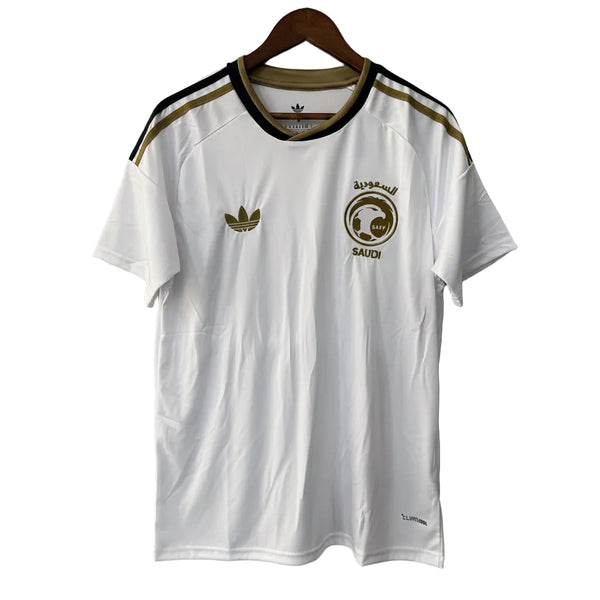White t-shirt with Adidas logo and Saudi Arabia emblem on a hanger against a gray background
