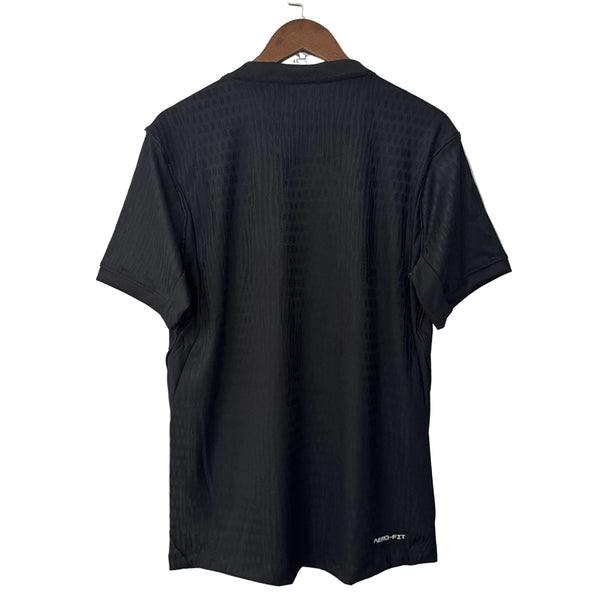 Black t-shirt on a hanger against a white wall