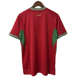 Red shirt with green sleeves on a hanger against a white background