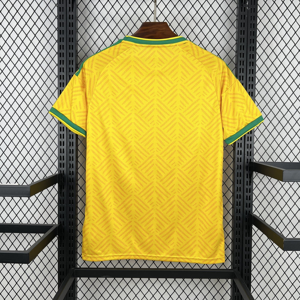 Yellow sports jersey with green accents on a black metal rack.