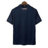 Navy blue polo shirt on a hanger against a white wall