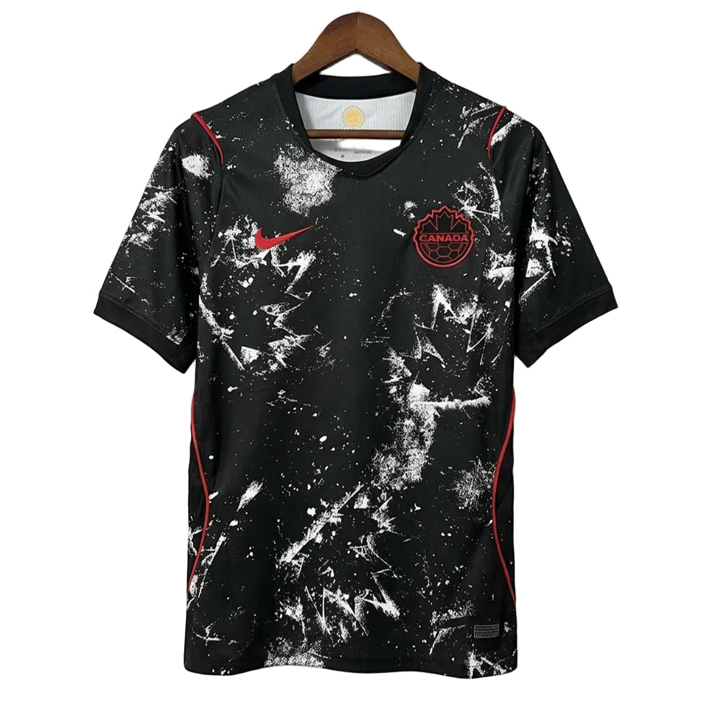 Black sports jersey with white splatter design and red accents on a hanger against a gray background