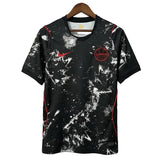 Black sports jersey with white splatter design and red accents on a hanger against a gray background