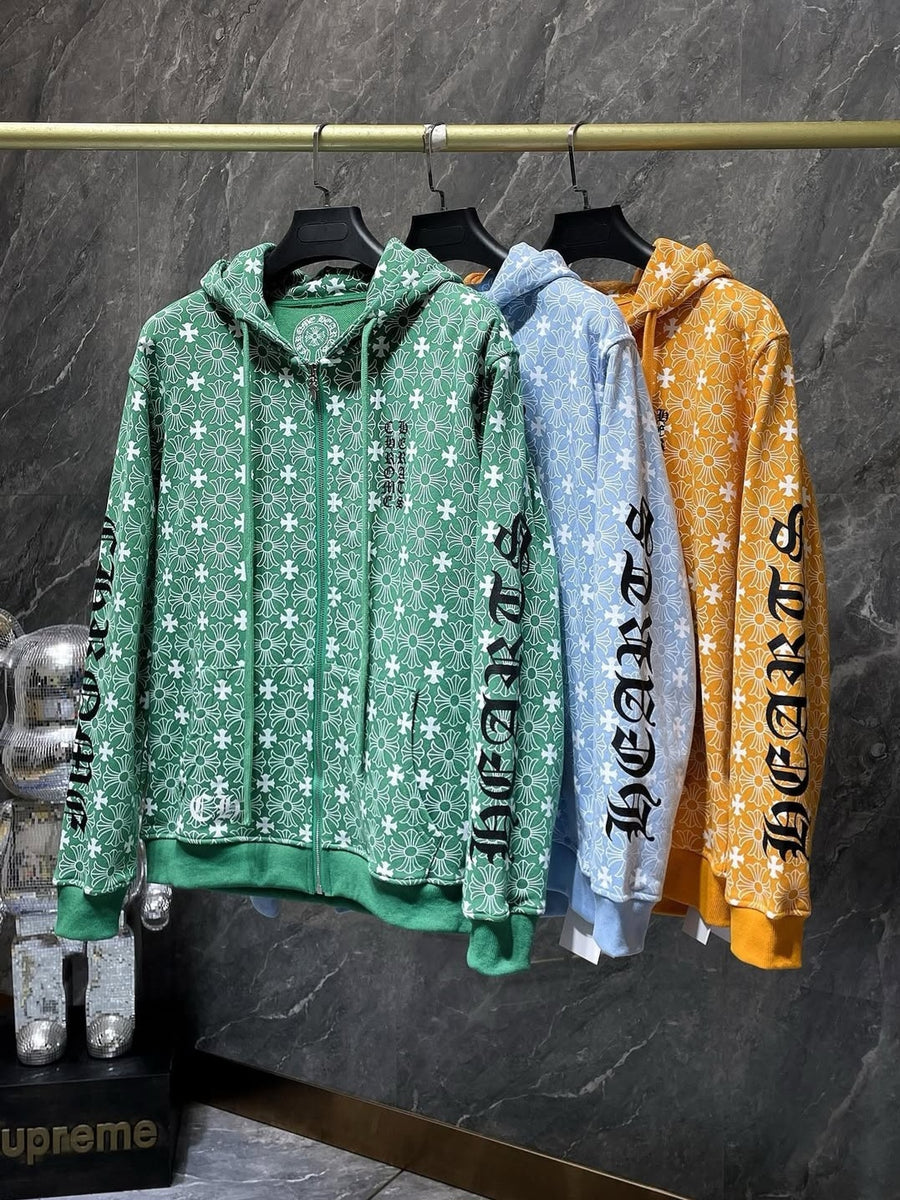 Three hoodies in green, blue, and orange hanging on a rack against a dark marble wall.
